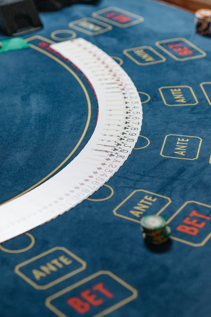 Close-up of a casino table featuring playing cards fanned out and poker chips for gambling.