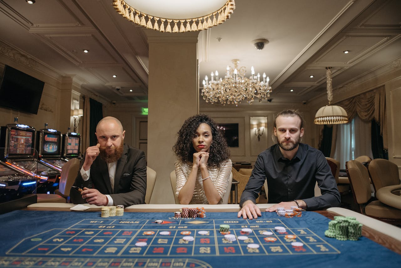 A diverse group of adults sitting at a casino gaming table with chips and cards in a luxurious setting.