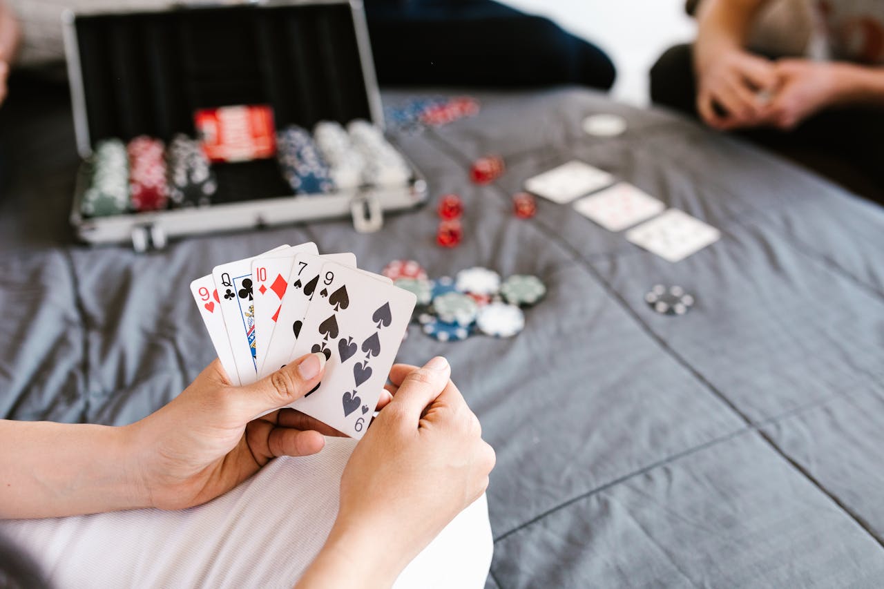 Close-up of a poker game with playing cards and chips on a table. Focus on player's hand.